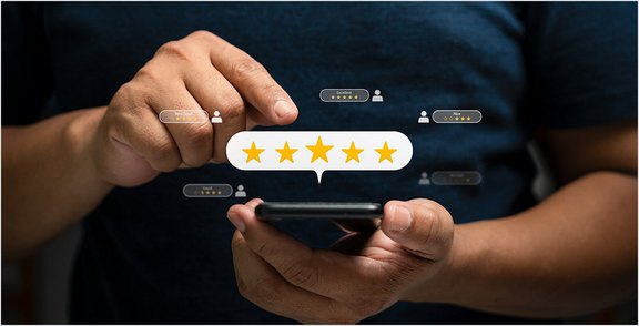 Person hält Smartphone mit einer Fünf-Sterne-Kundenbewertung und Feedback-Sprechblasen auf dem Bildschirm.